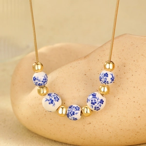 Detail showing blue floral ceramic beads and 18K gold-plated chains on a wavy stand