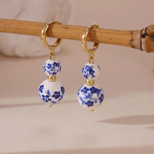 Blue and white porcelain bead earrings with gold rings on a bamboo branch stand