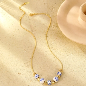 Detail of 18K gold plated chain necklace with blue and white porcelain beads and extension