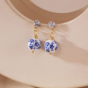 Detail of blue and white porcelain heart earrings with gold metal and white zircon stud