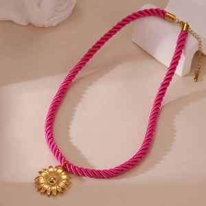 Detail der goldenen Sonnenblume am leuchtend rosa geflochtenen Kordel-Halskette