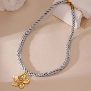 Detailansicht eines 18K Gold-Blumenanhängers mit blauem Seidenseil und feiner Textur