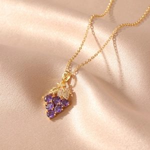 Detailed macro view of purple gemstone grape pendant on a fine gold stainless steel chain