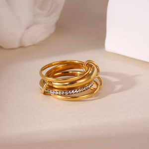 Vista macro di anelli d'oro a strati con pavé di zirconi e maglie intrecciate