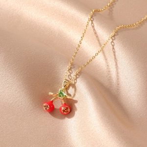 Macro view of a gold-tone cherry pendant featuring red fruit and yellow crystals