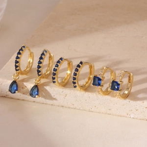 Detailed shot of three gold hoop earrings set with navy blue and clear cubic zirconia stones