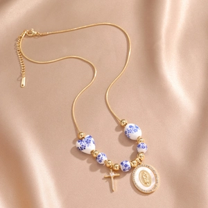 Detailed close-up of a blue and white porcelain bead necklace with gold cross charms