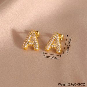 Elegantes pendientes de letra A dorados con circonitas sobre seda color champán