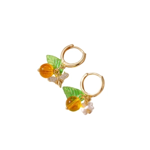 Pendientes de aro dorados con colgantes de abeja flor y fruto con hojas verdes sobre blanco