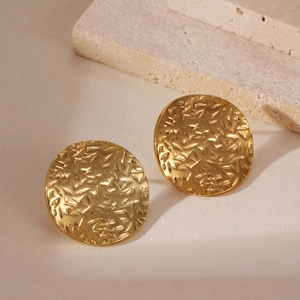 Dettaglio macro di orecchini tondi placcati oro 18k con texture metallica martellata