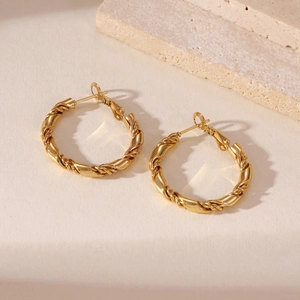 Dettaglio di orecchini a cerchio intrecciati placcati oro 18k con finitura strutturata