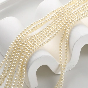 Detailed macro shot of 4-6mm round cream white pearl strands with soft luster on a white stand