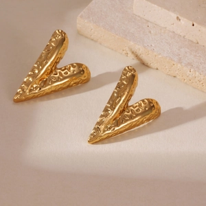 Dettaglio di orecchini in acciaio placcati oro 18k con superficie martellata artistica