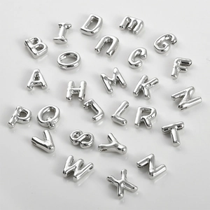 Macro shot of 26 polished silver 14k gold-filled uppercase alphabet beads for DIY jewelry