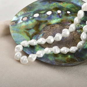 Detailed close-up of baroque style irregular glass pearls on a soft beige fabric background