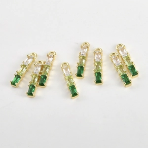 Macro shot of gold-plated bamboo-style charms with green gradient baguette-cut zircons