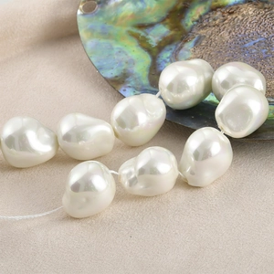 Macro view of irregular Baroque glass pearls with iridescent luster on linen and shell