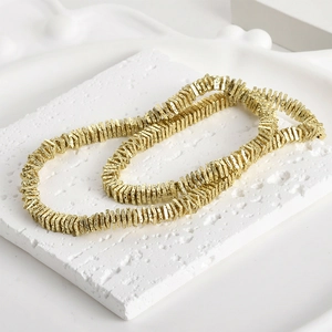 Golden volcanic stone square beads on a textured white stone backdrop for jewelry making