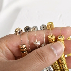 Detailed macro view of 4mm gold and silver flat disc beads with lava texture for DIY jewelry