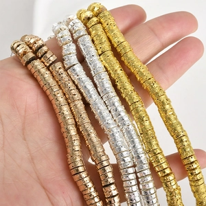 Macro shot of 4mm gold and silver lava wheel beads held by hand for jewelry making