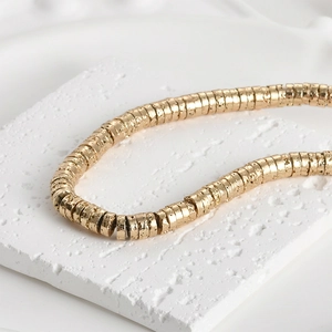 Macro shot of 4mm gold-plated volcanic stone wheel beads with hammered texture