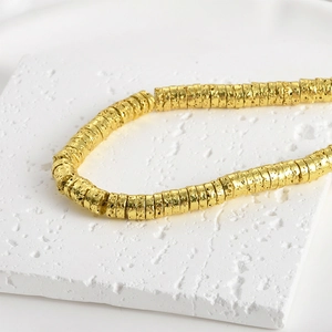 Macro detail of 4mm gold plated lava stone wheel beads with unique hammered texture