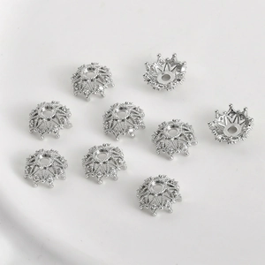 Detalle de cuentas de corona plateadas con pedrería para creación de joyería DIY