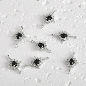 Detail of 14k gold-plated starburst charms with black stones and zircon for DIY jewelry