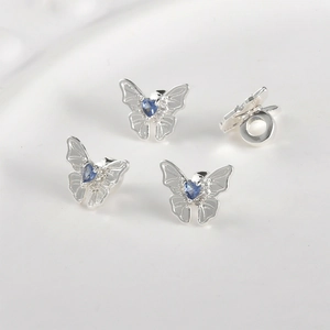Close-up of four silver butterfly charms with blue heart zircon for DIY jewelry making