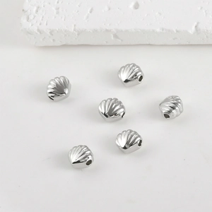 Macro view of shell-shaped metal beads with vertical holes for DIY jewelry making