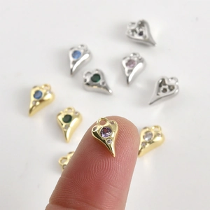 Mini pendentifs en forme de cœur plaqués or 14k avec zircons colorés sur le bout d'un doigt