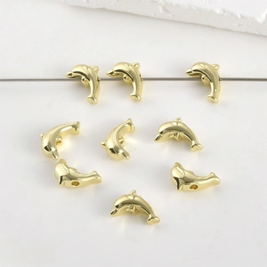 Macro view of 14k gold-plated dolphin-shaped spacer beads for DIY jewelry making