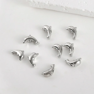 Close-up of dolphin-shaped silver plated metal beads for DIY jewelry making and crafts