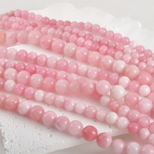 Detailed macro view of 8mm natural Persian jade round beads in soft peach pink hues