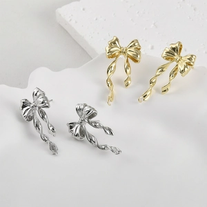 Detailed view of 14k gold plated bow earrings with twisted spiral long dangles