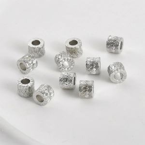 Macro shot of silver textured cylinder beads with intricate woven pattern for DIY jewelry