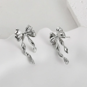 Detailed view of silver bow earrings with elegant twisting tassels and a polished finish