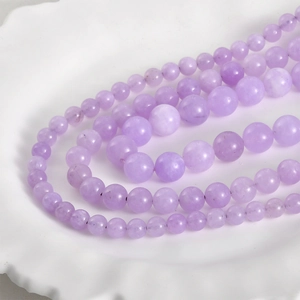 Macro detail of 8mm lavender Persian jade round beads on a decorative white porcelain plate