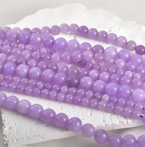 Macro shot of 8mm polished lavender Persian jade round beads on a white marble stone base