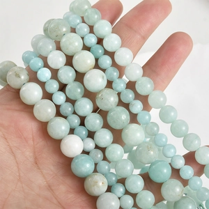 Detailed view of hand-held light blue natural stone round beads for DIY jewelry making