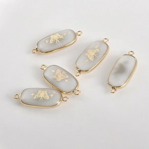Detail of oval natural stone jewelry connectors with gold butterfly and star patterns
