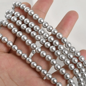 Close-up of 8mm silver-grey round glass pearl beads with metallic luster on hand