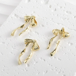 Close-up of three 14k gold-plated bow pendants for DIY jewelry making on white stone