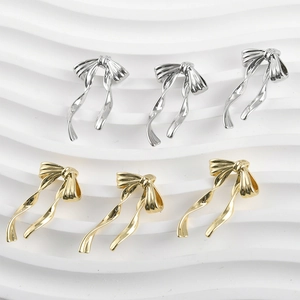 Macro detail of 14k gold and silver plated ribbon bow tassel pendants for DIY jewelry