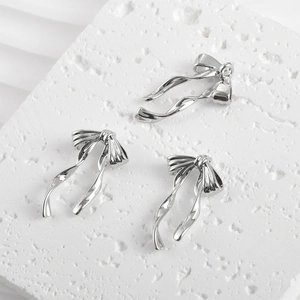 Polished silver bow pendant charms for jewelry making on a stone background