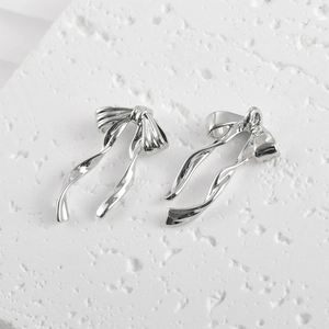 Close-up of polished silver bow-knot charms showing front and back detail for DIY jewelry
