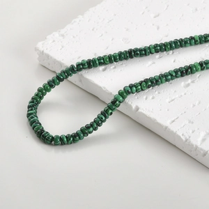 Close-up of natural malachite beads with green and black wavy patterns for jewelry