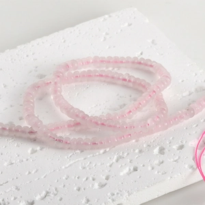 Close-up of natural light pink quartz flat beads on textured white display board