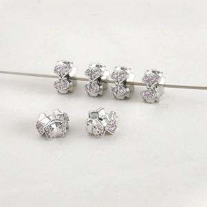 Macro view of six bow-shaped beads with micro-set pink zircons and silver finish