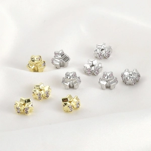 Macro detail of 14k gold-plated bowknot spacers with pink cubic zirconia on silk
